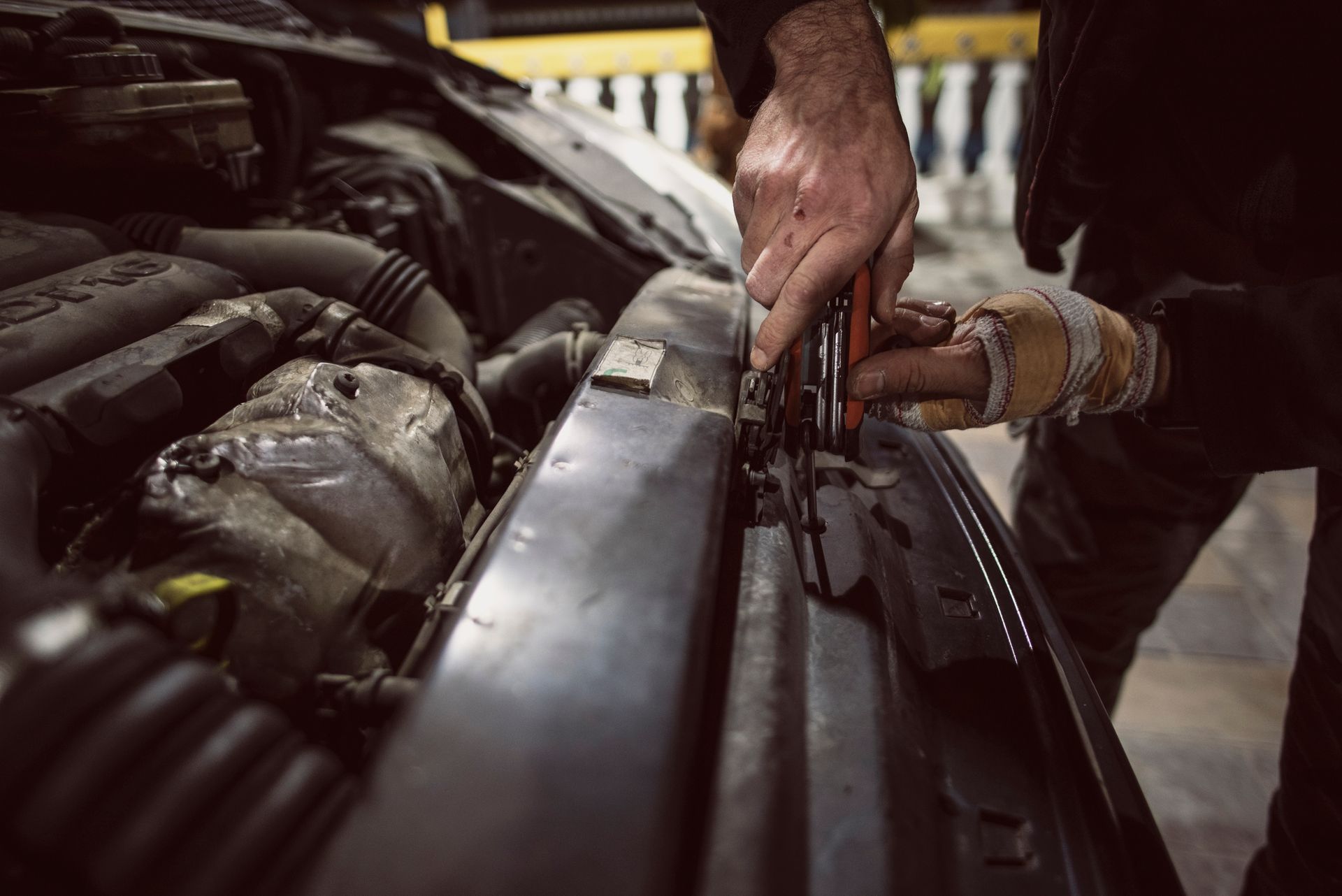 A man is working on the radiator of a car with a wrench.