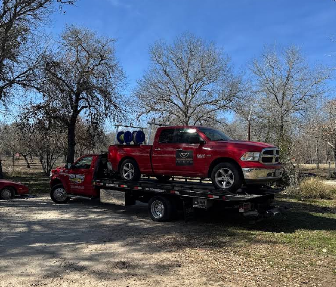 A red truck is being towed by a tow truck.