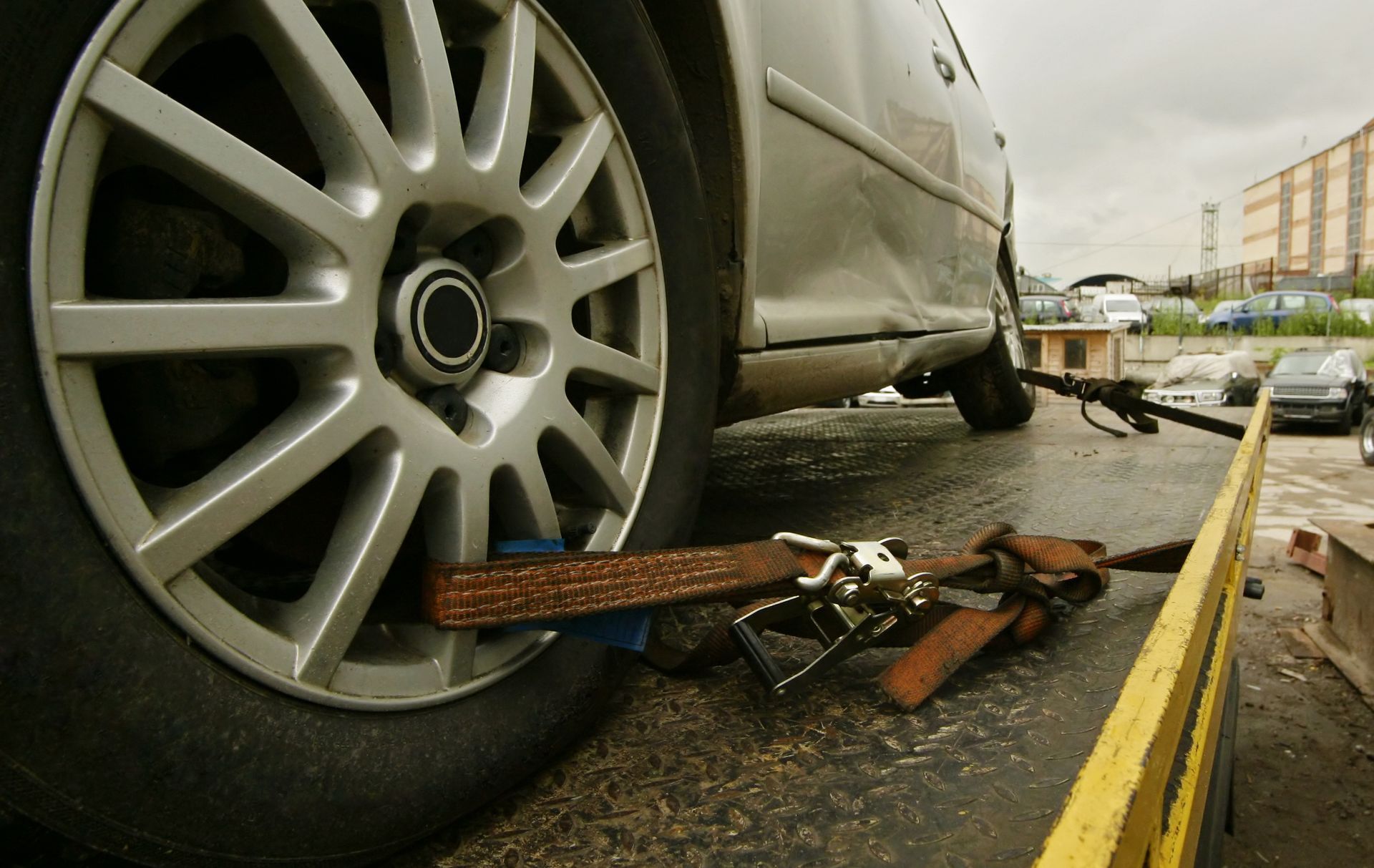A silver car is being towed by a tow truck