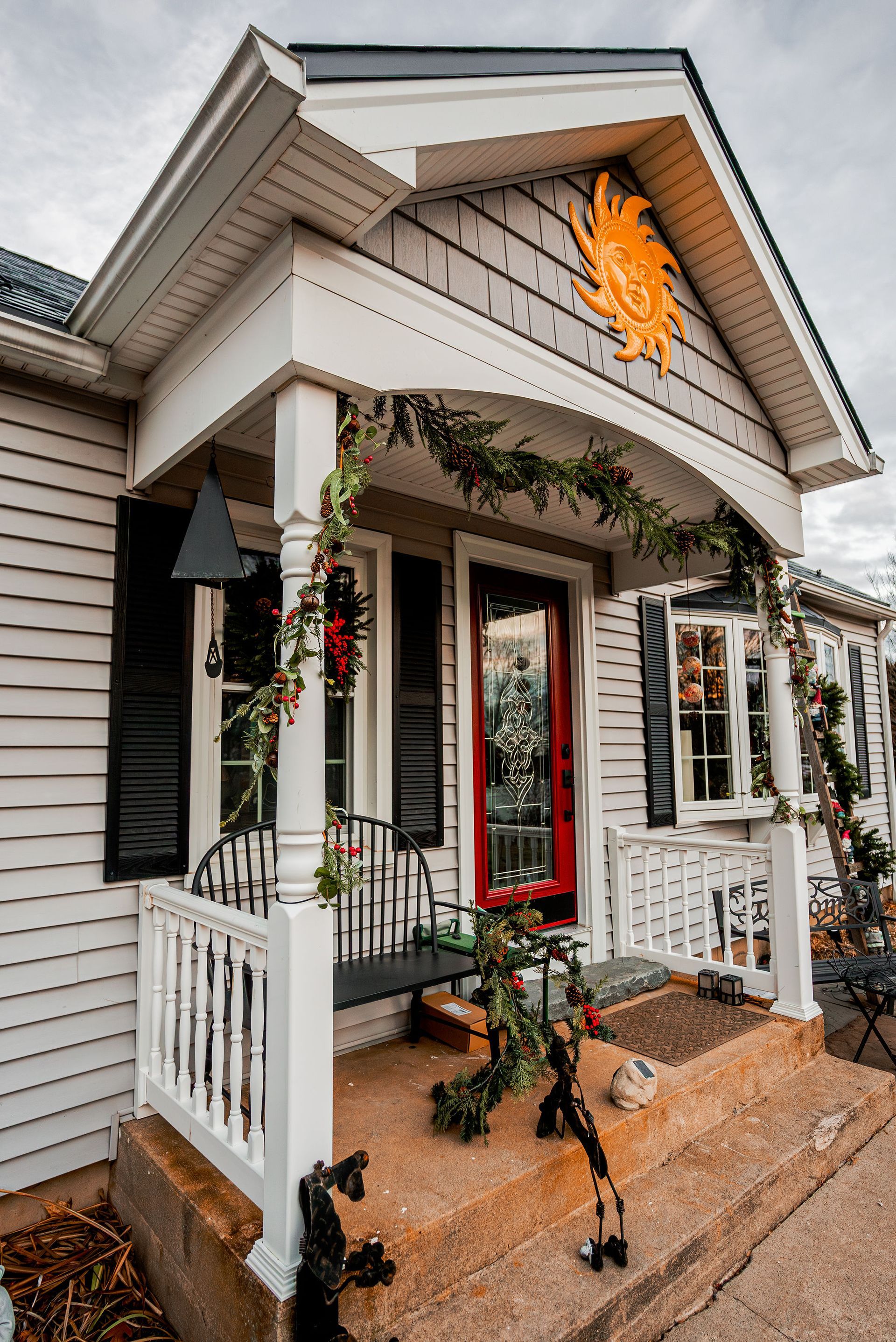 A festive house entrance with garlands, a red door, and a sunburst decoration.