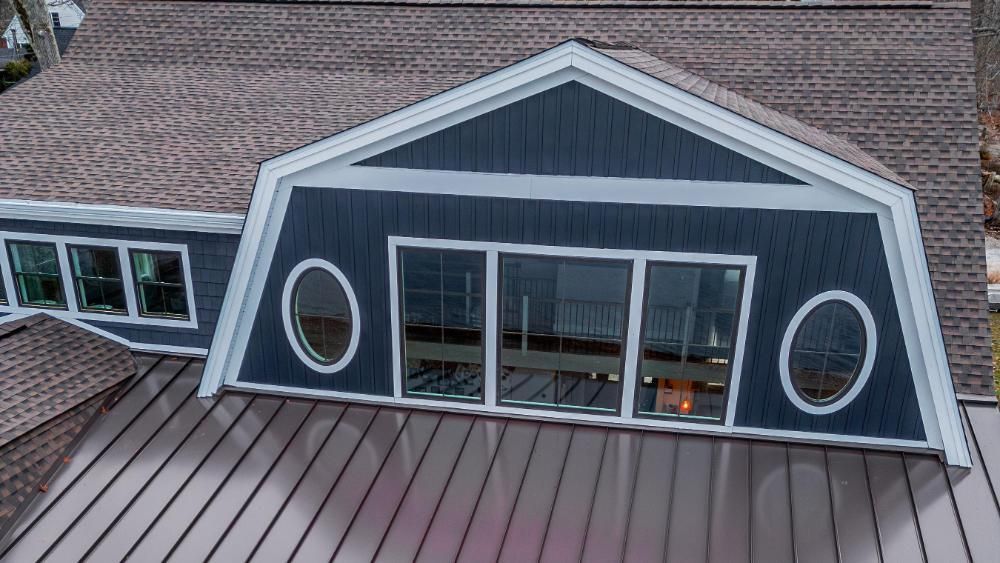 An aerial view of a house with a roof that looks like a barn.