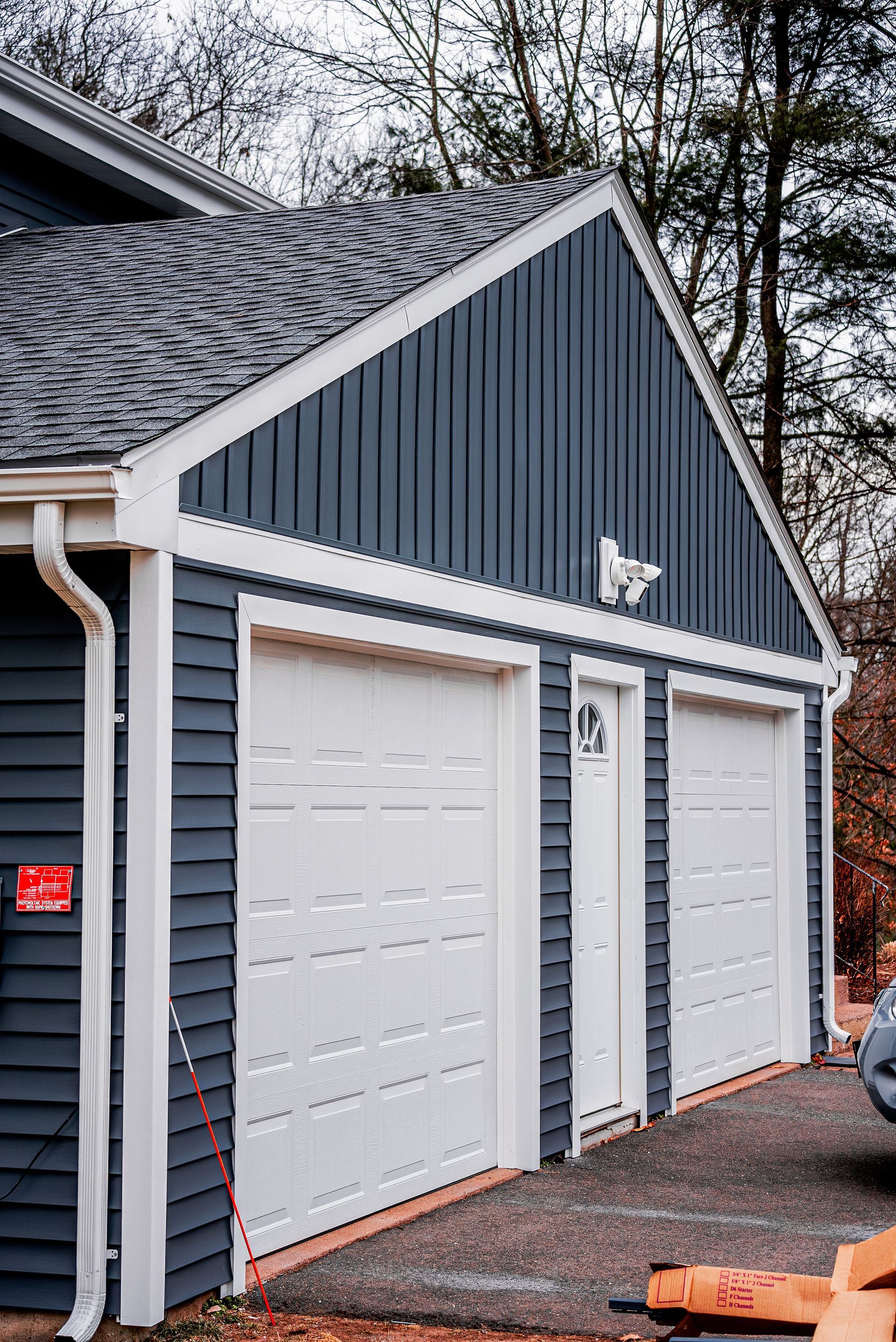 Two-car garage with dark blue siding, white doors/trim, and a gray roof.
