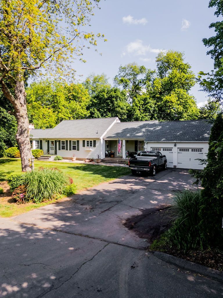 Ranch-style house with a black pickup truck parked in front of a two-car garage on a sunny day.