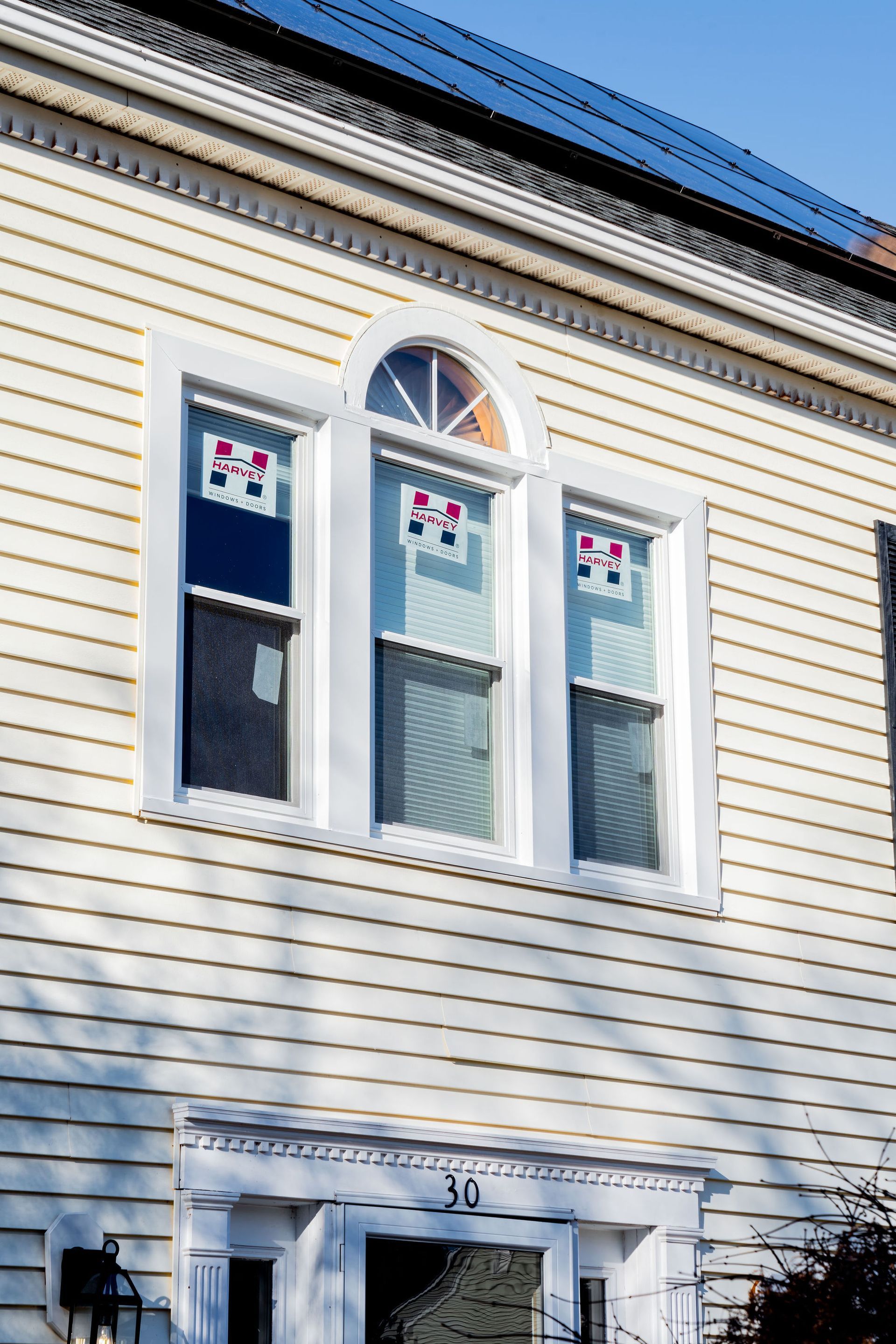 Exterior view of a cream-colored building with three white-framed windows, decorative trim, and the number 30.