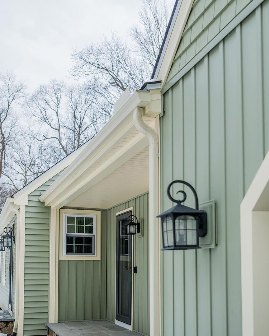 A green house with a porch and a lantern on the side