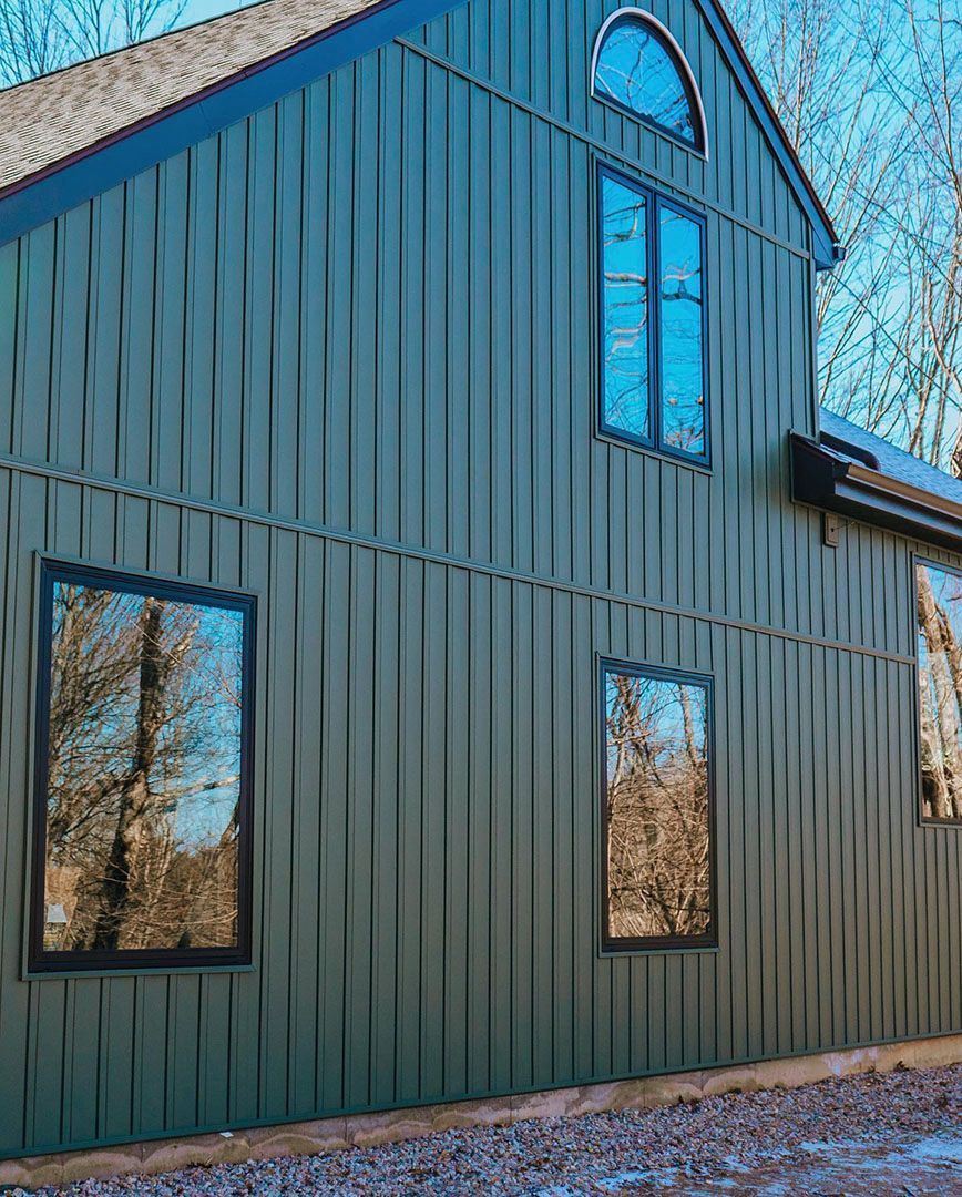 A green house with a lot of windows and trees reflected in the windows.