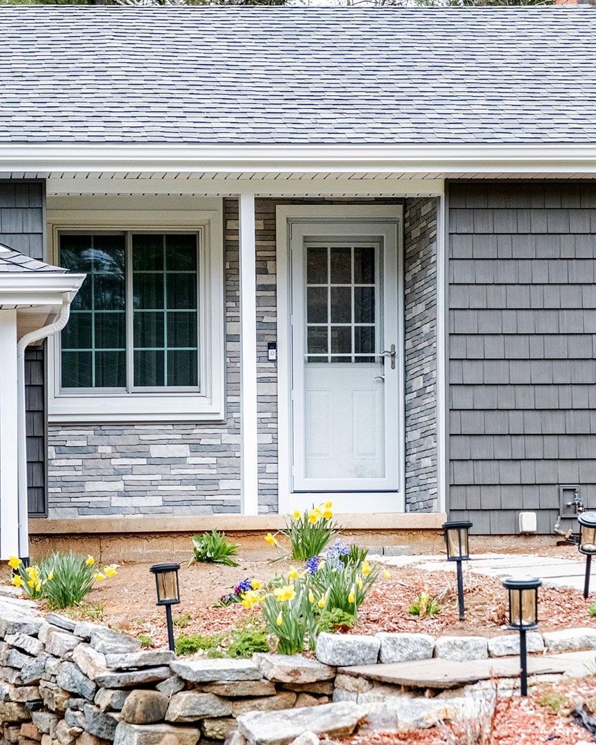 The front of a house with a white door and a stone wall.