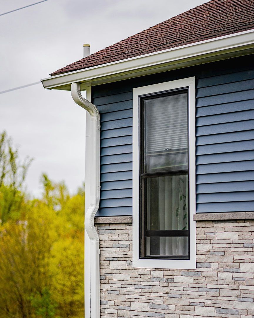 A blue house with a window and a gutter on the side.