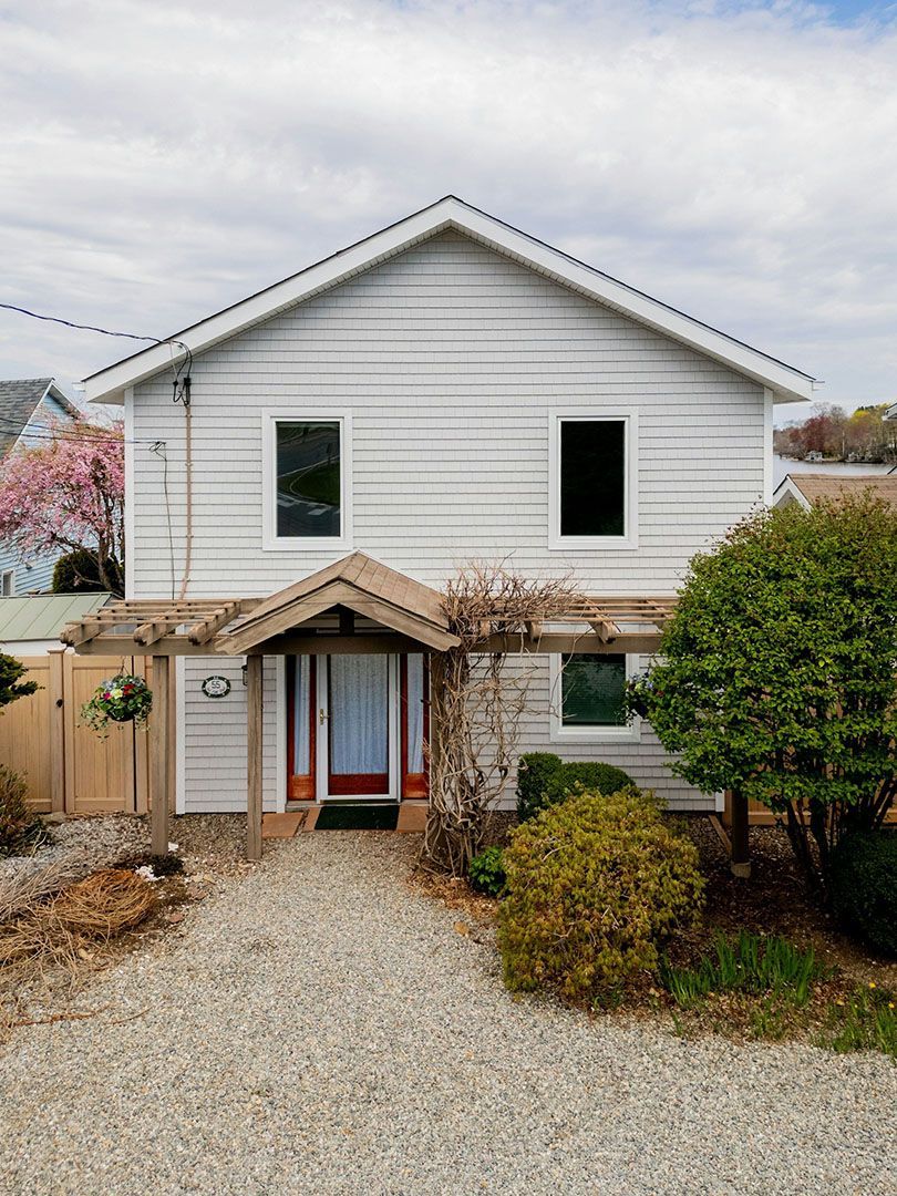 A white house with a gravel driveway in front of it.