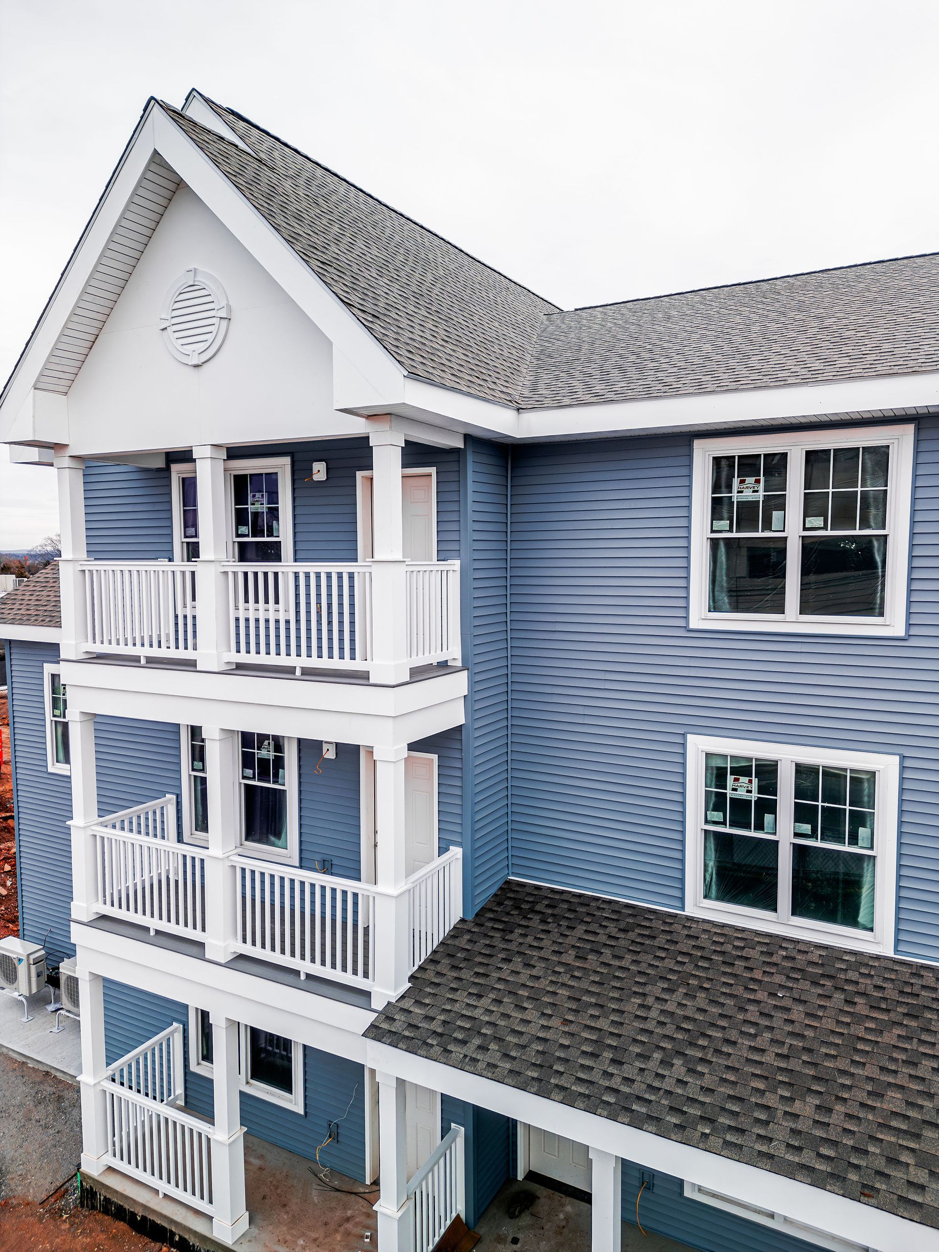 Blue multi-story building with white balconies, gray roof, and windows.
