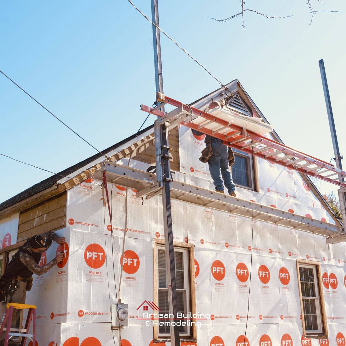 A man on a ladder is working on the side of a house