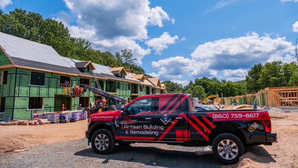 A red and black truck is parked in front of a building under construction.