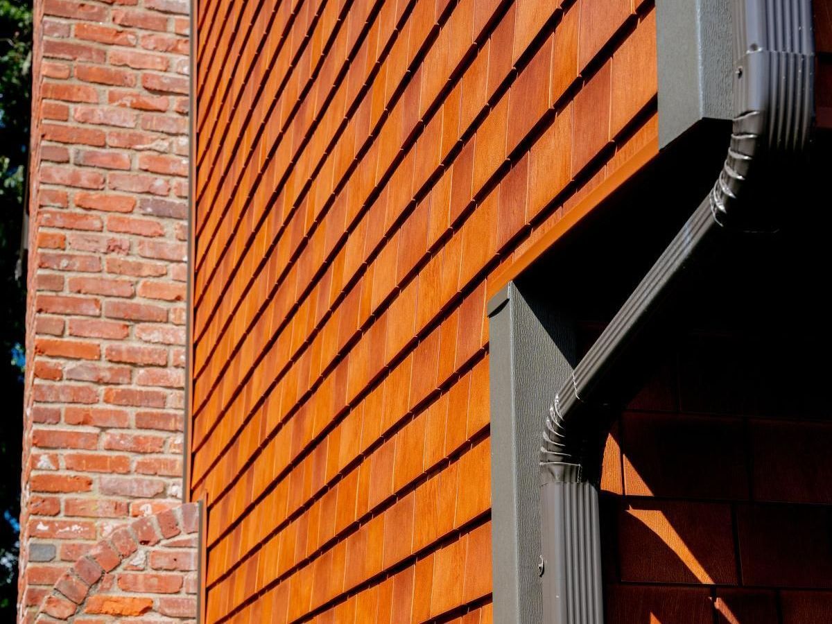 A close up of a house with a gray siding and white windows.