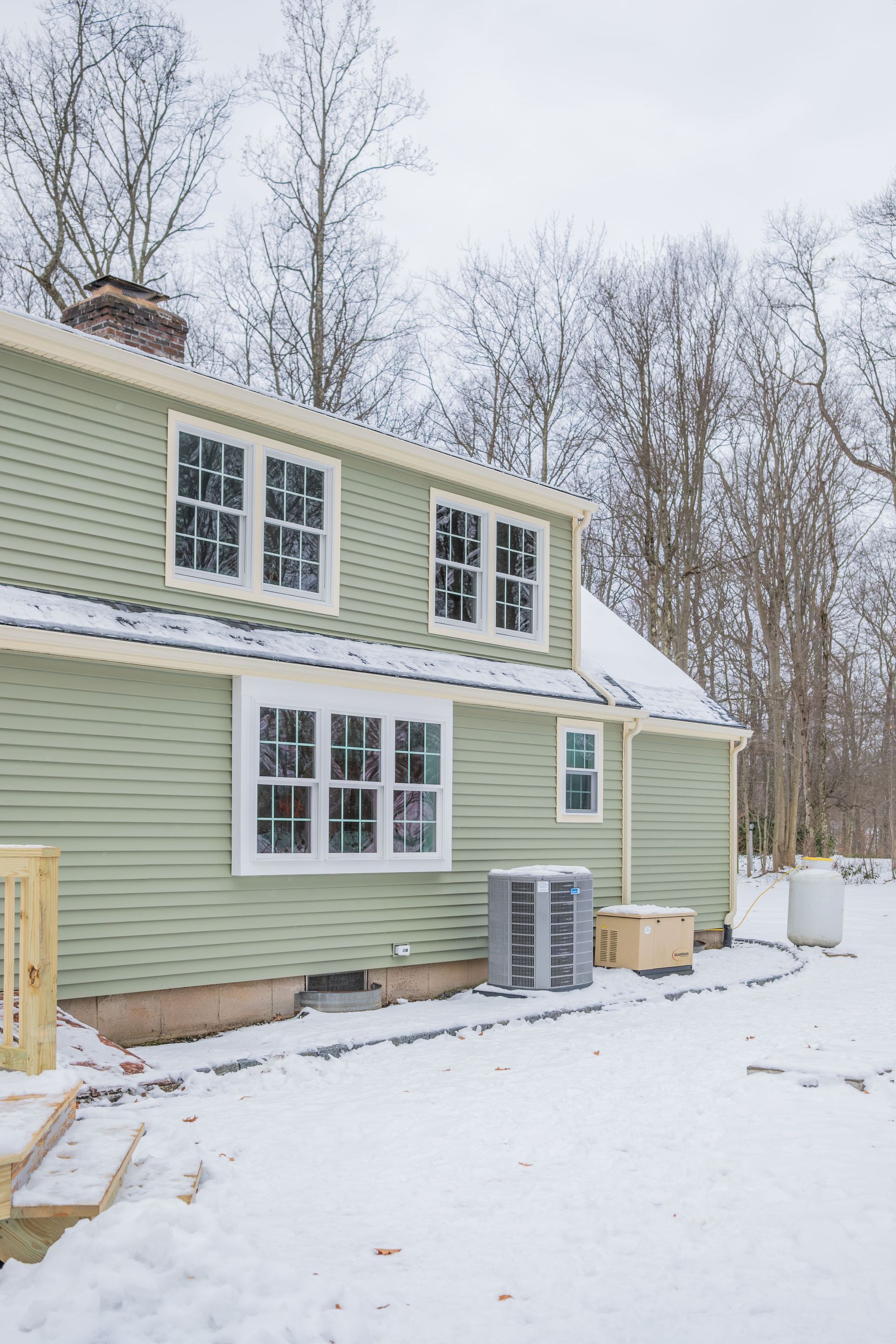 A green house with a lot of windows is covered in snow.