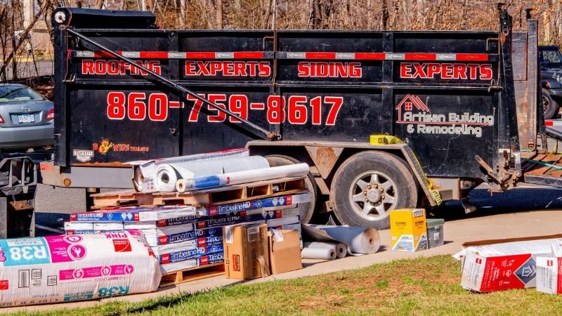 A dump truck with a phone number on the back is parked on the side of the road.