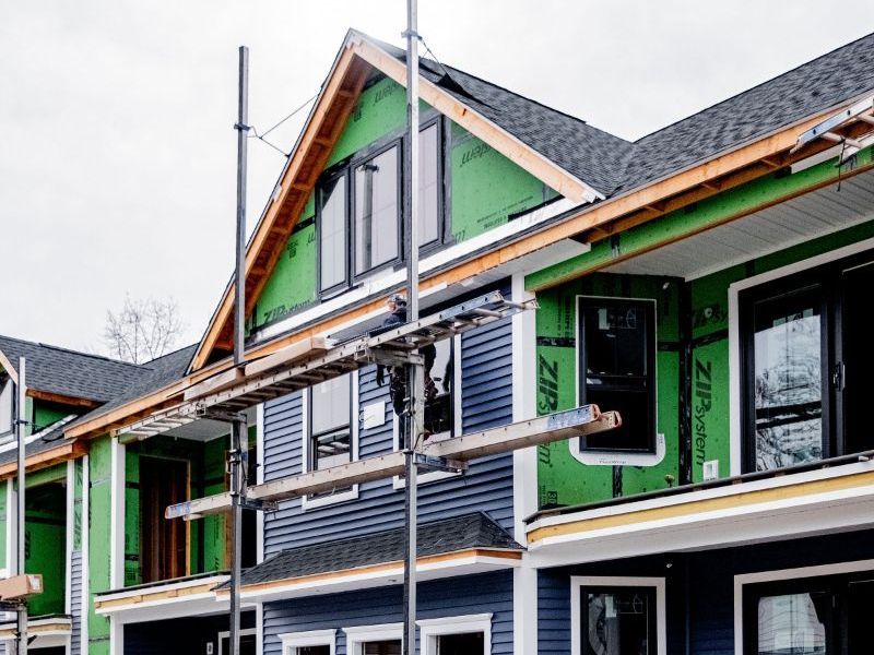 A row of houses under construction installing vinyl siding