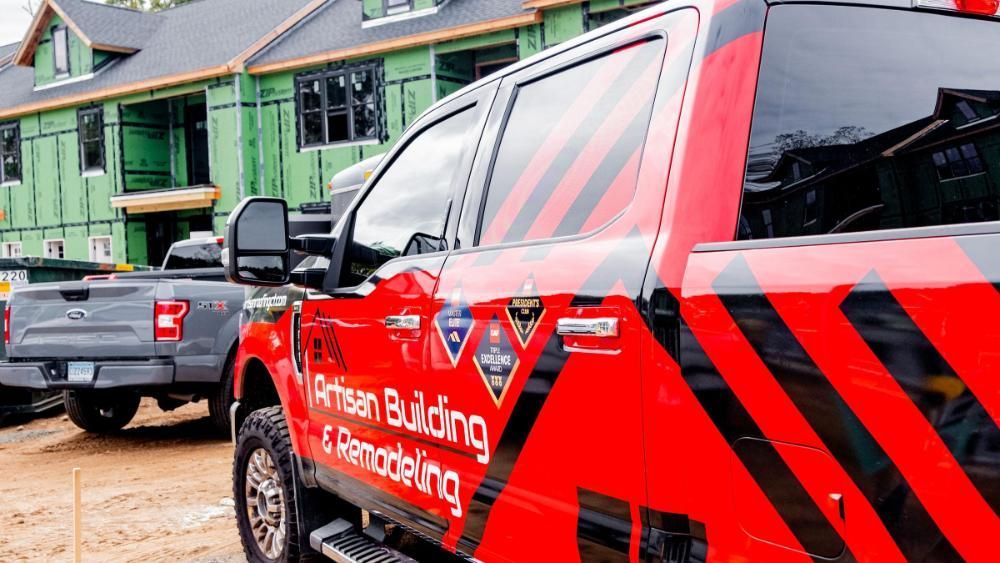 A red truck is parked in front of a house under construction.