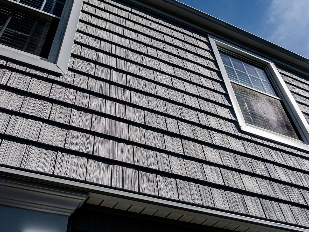 A close up of a house with shingles on the side and a window.