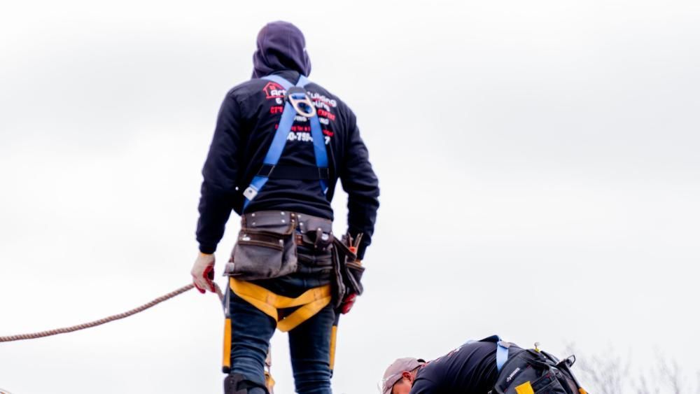 A man is standing on top of a roof holding a rope.