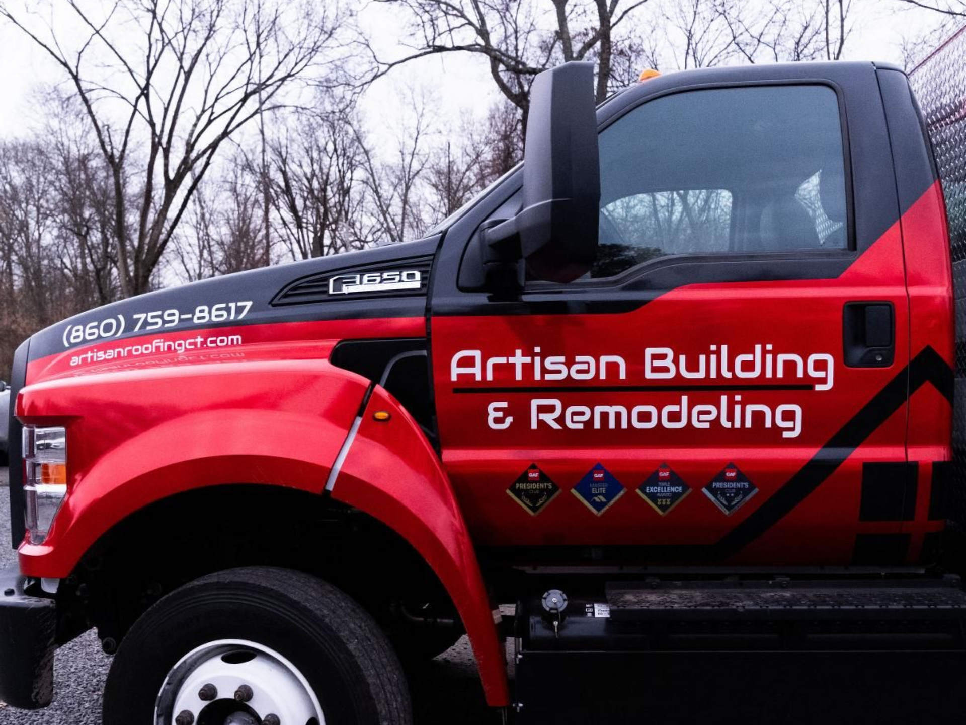 Red Artisan Building & Remodeling truck with business details parked outdoors on an overcast day.