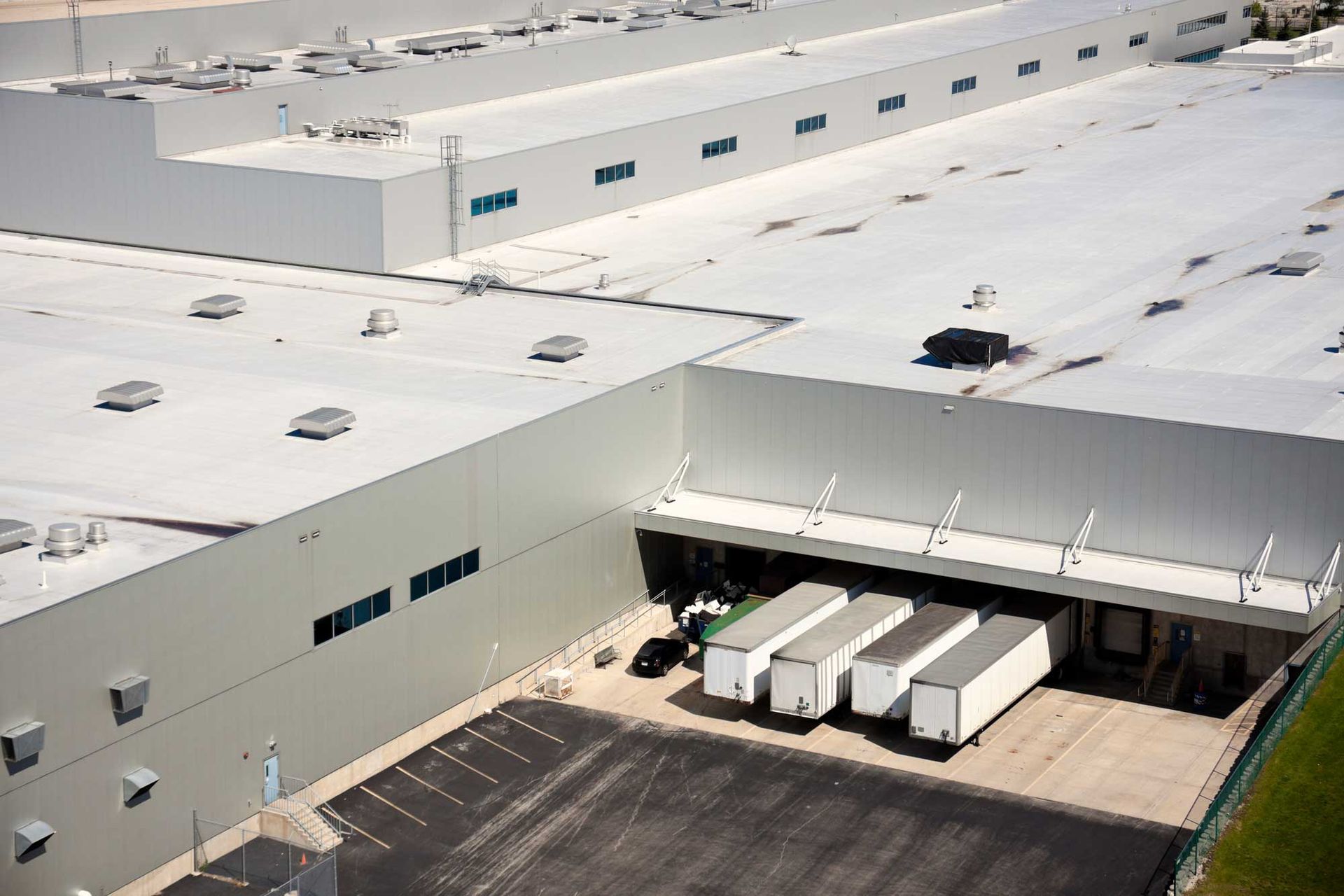 An aerial view of a large white building with trucks parked in front of it