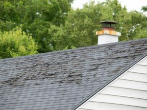 A roof with a chimney on top of it and trees in the background.