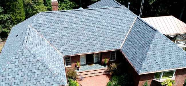 An aerial view of a large brick house with a gray roof.