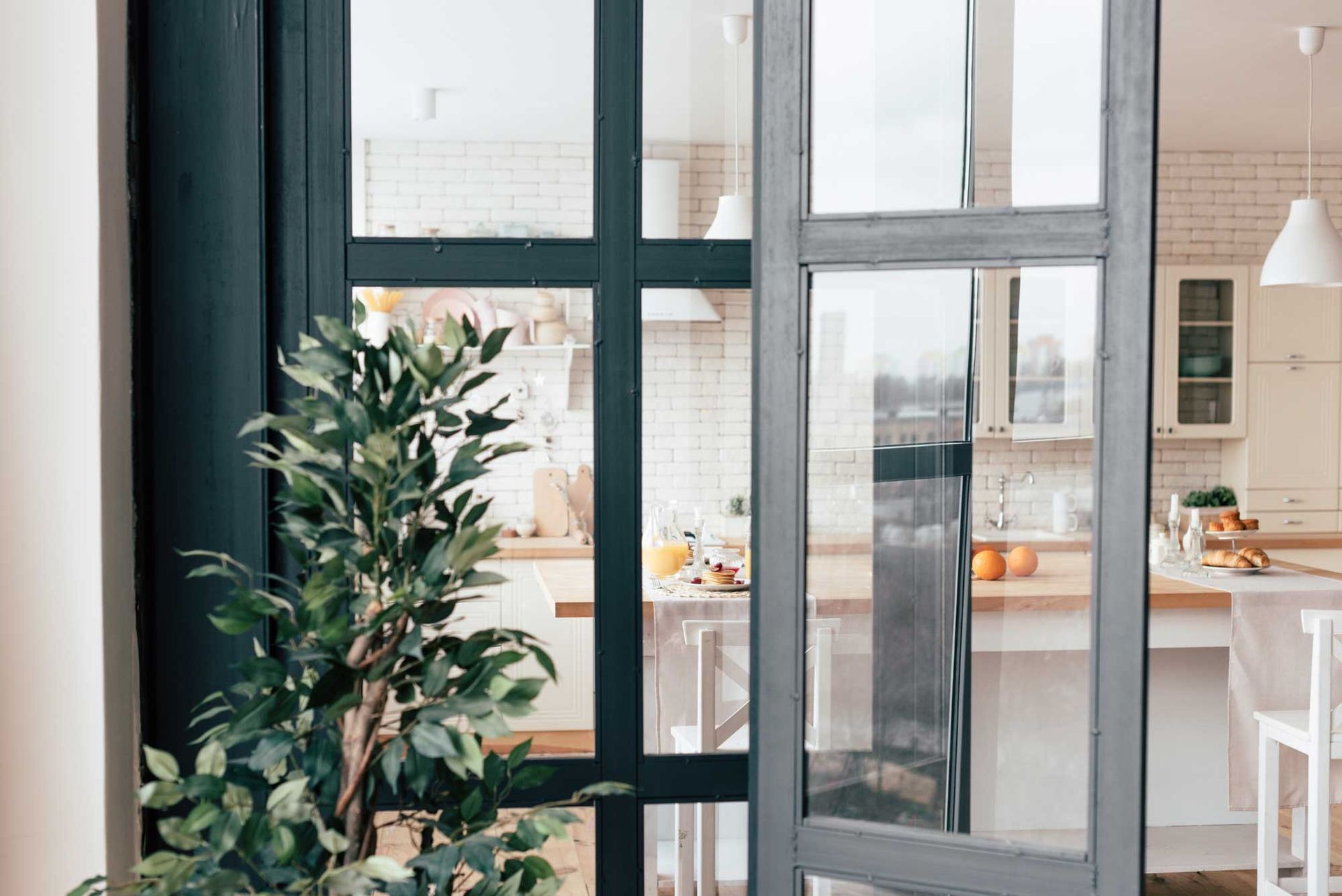 A plant is sitting in front of a glass door in a kitchen.