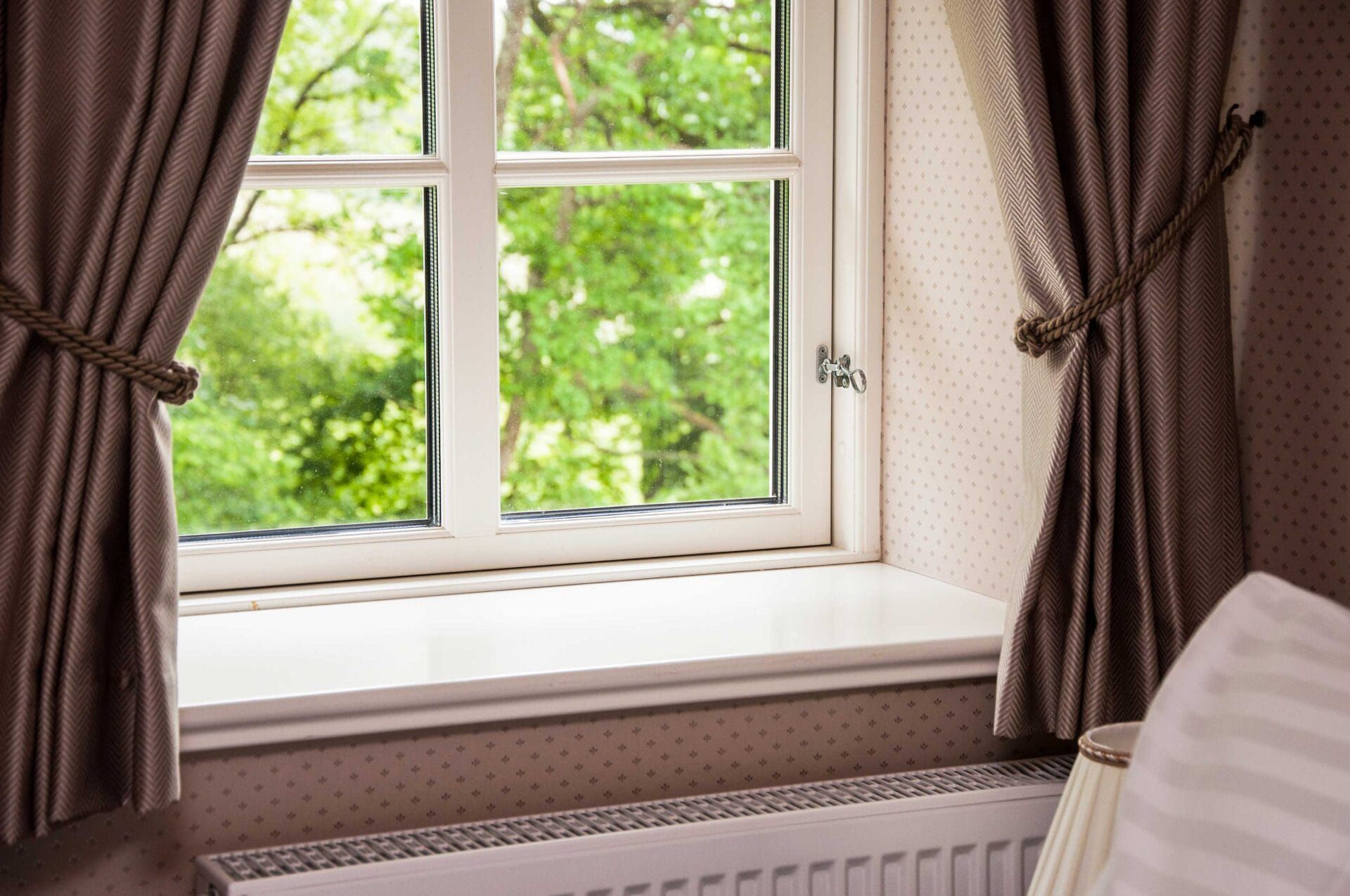 A bedroom with a bed and a window with a view of trees.