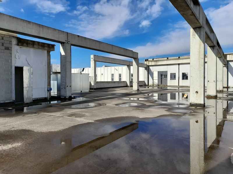 A building under construction with a puddle of water in front of it.