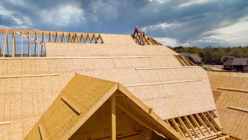 A man is working on the roof of a house under construction.