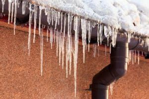 Icicles are hanging from the gutter of a building.