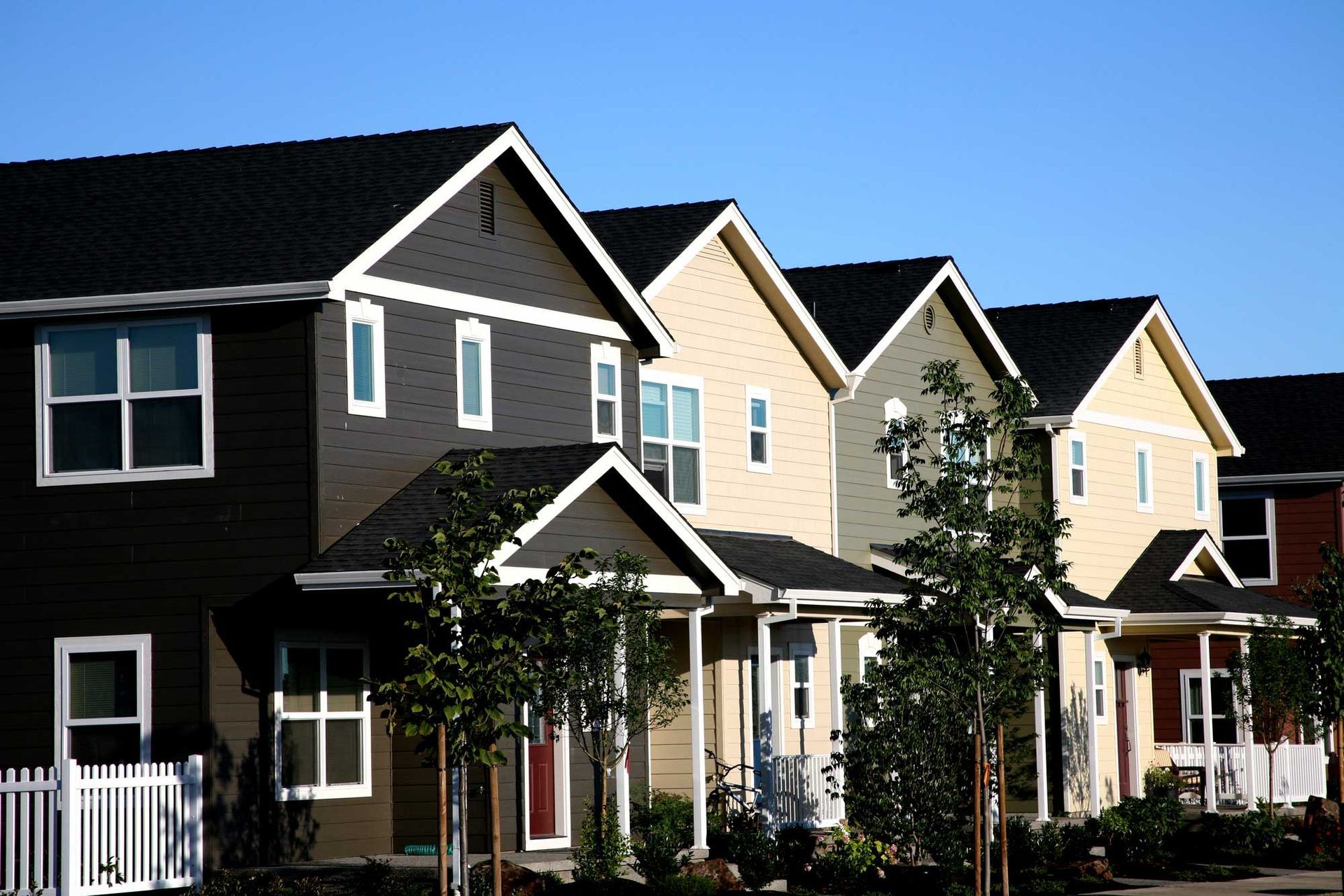 A row of houses with black roofs and white trim