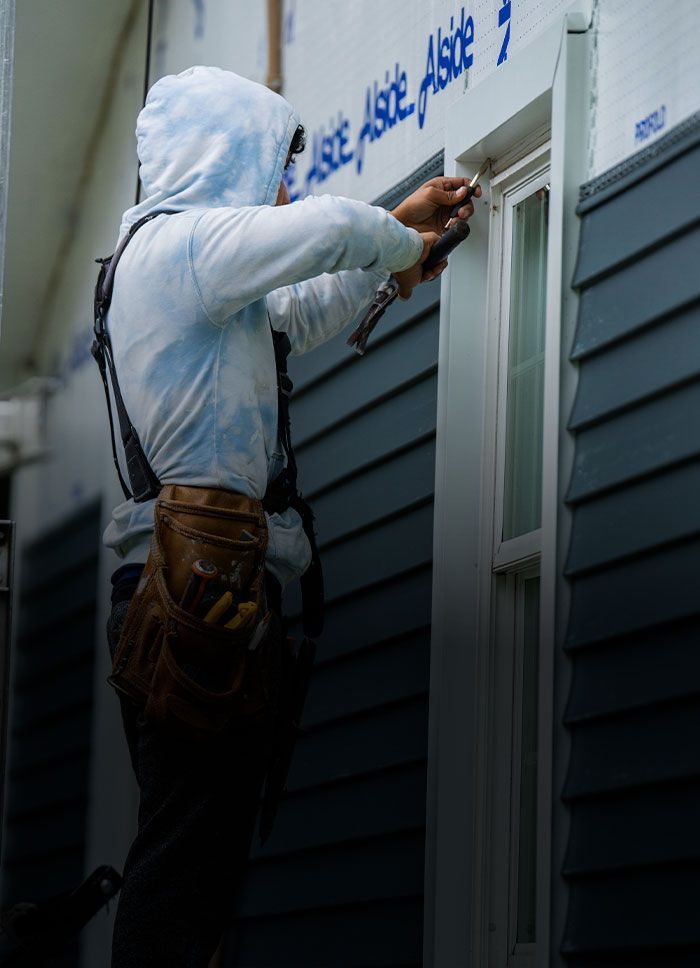 A man is fixing a window on a house.