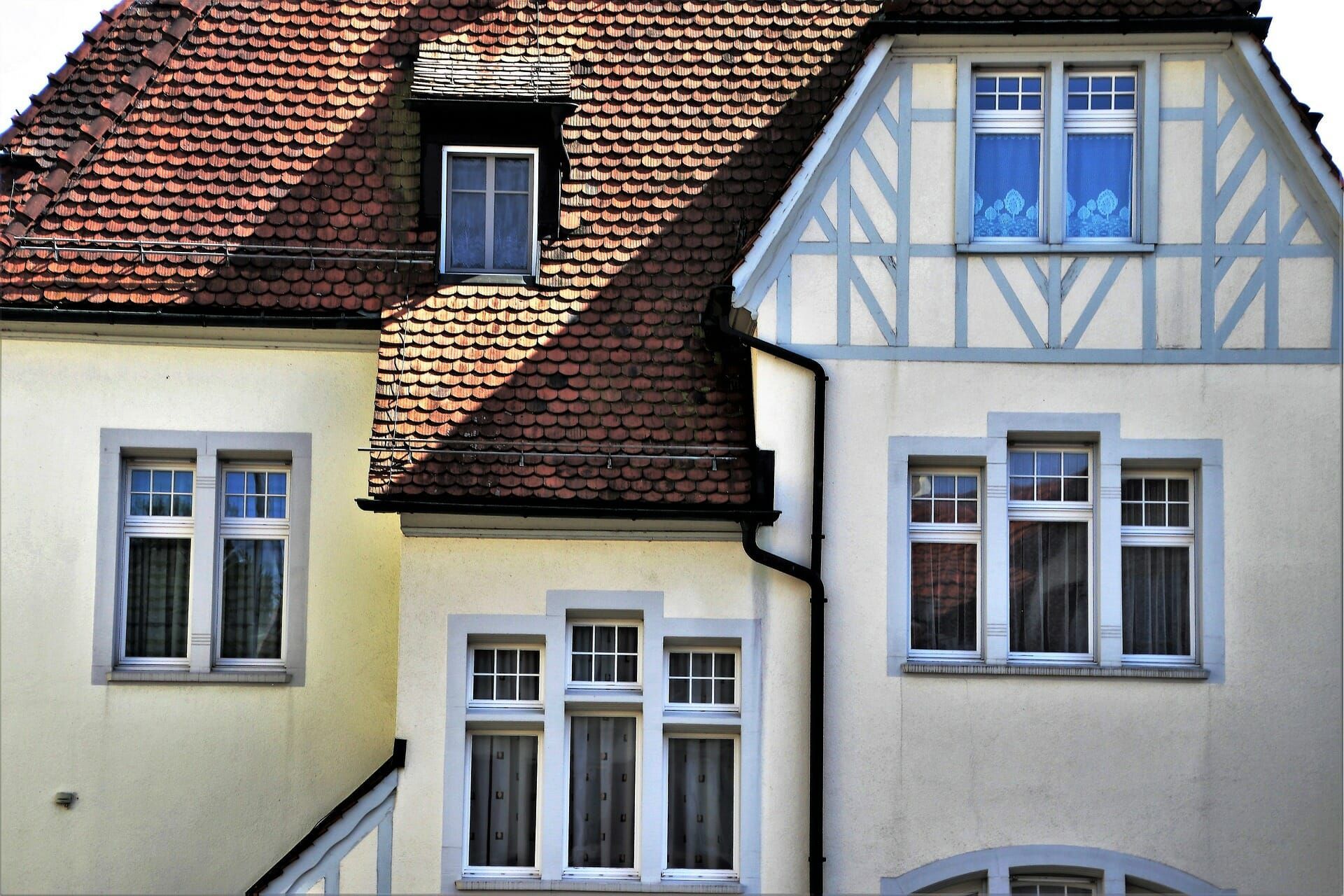 A white house with a brick roof and a lot of windows