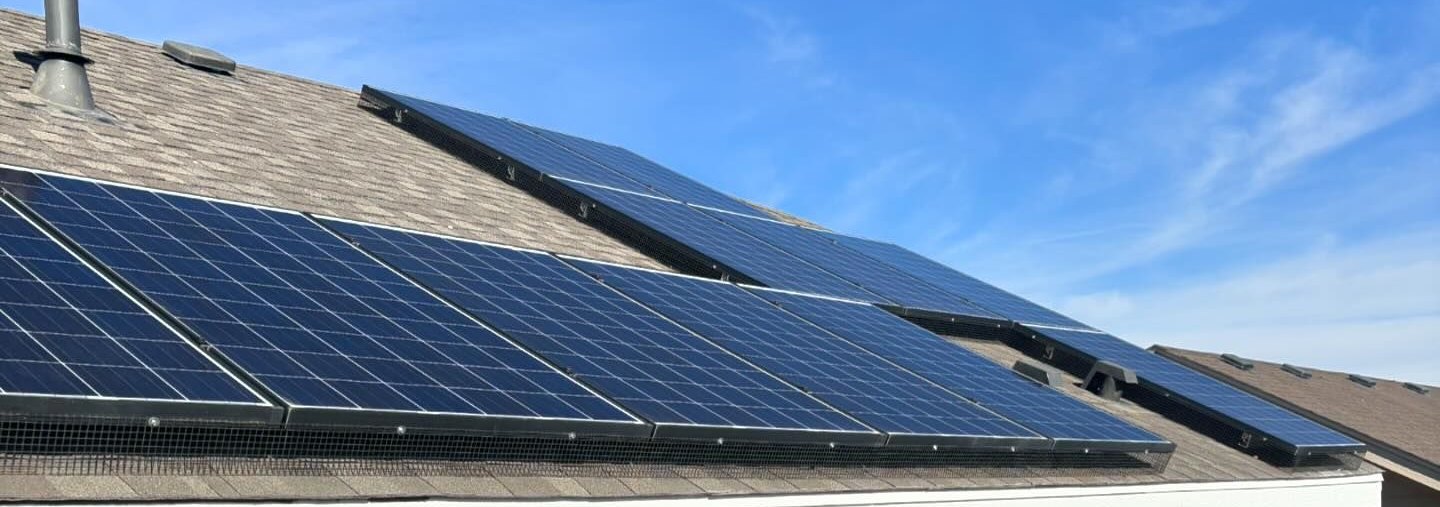 There are many solar panels on the roof of a house.