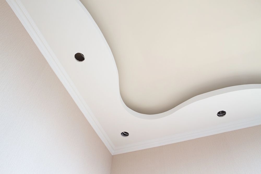 Soffitto bianco sporco con sezione curva incassata; luci e modanature integrate.