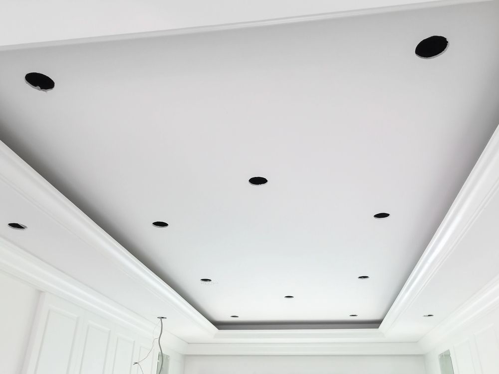 Soffitto bianco con illuminazione da incasso e modanature a corona.