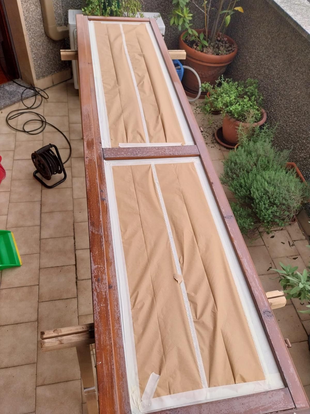 Porta in legno in fase di restauro all'esterno, ricoperta di carta marrone e nastro adesivo.