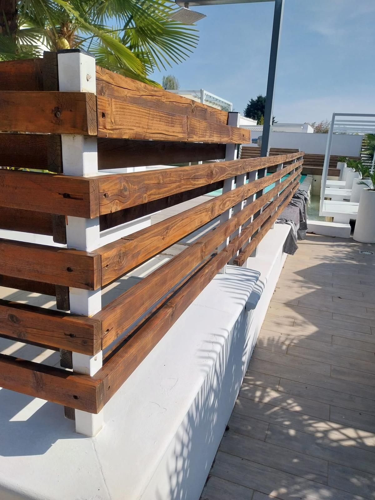 Ringhiera in legno e bianco su un ponte con cielo azzurro sullo sfondo.