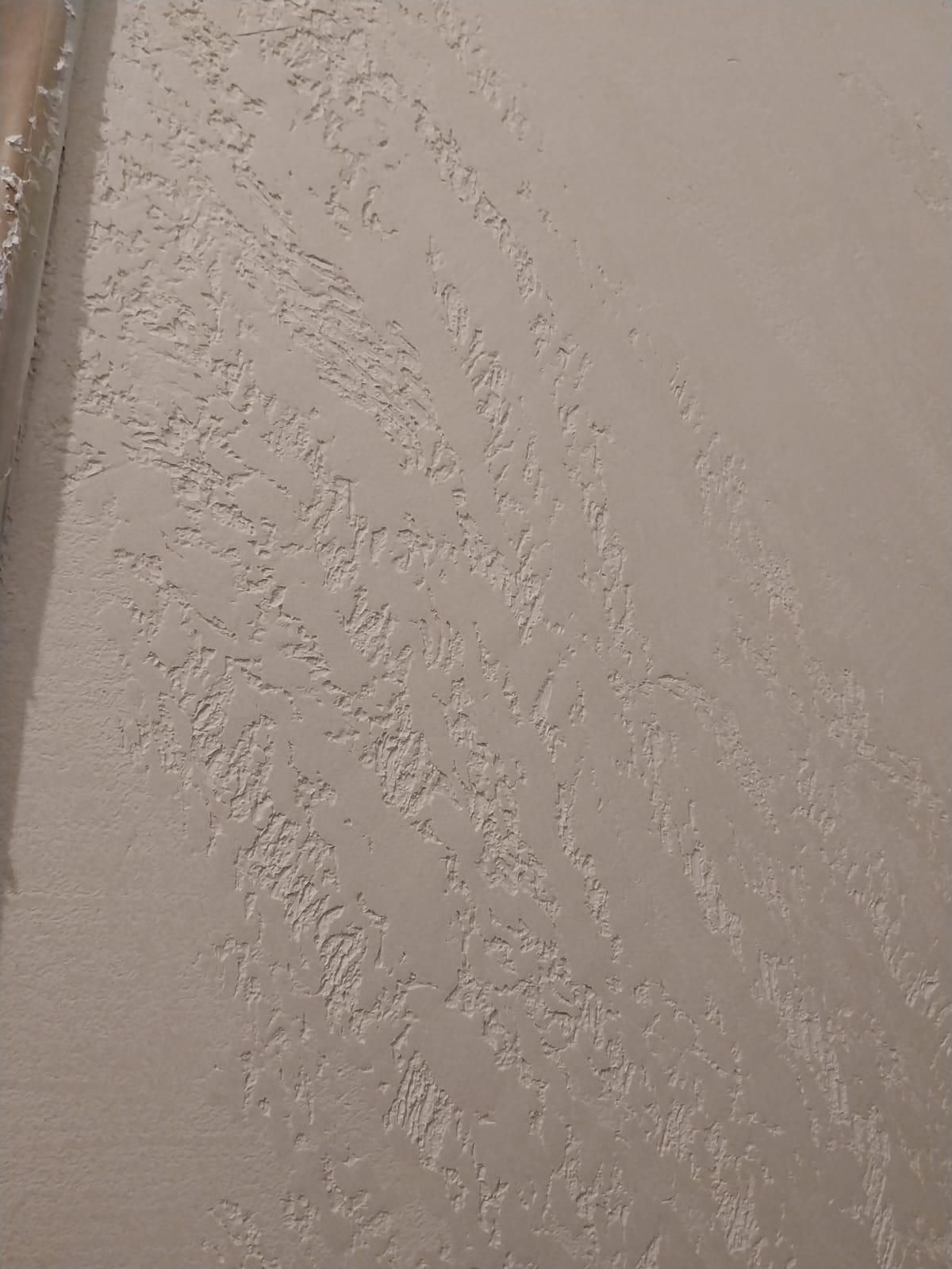 Superficie strutturata grigio chiaro con motivi sovrapposti.