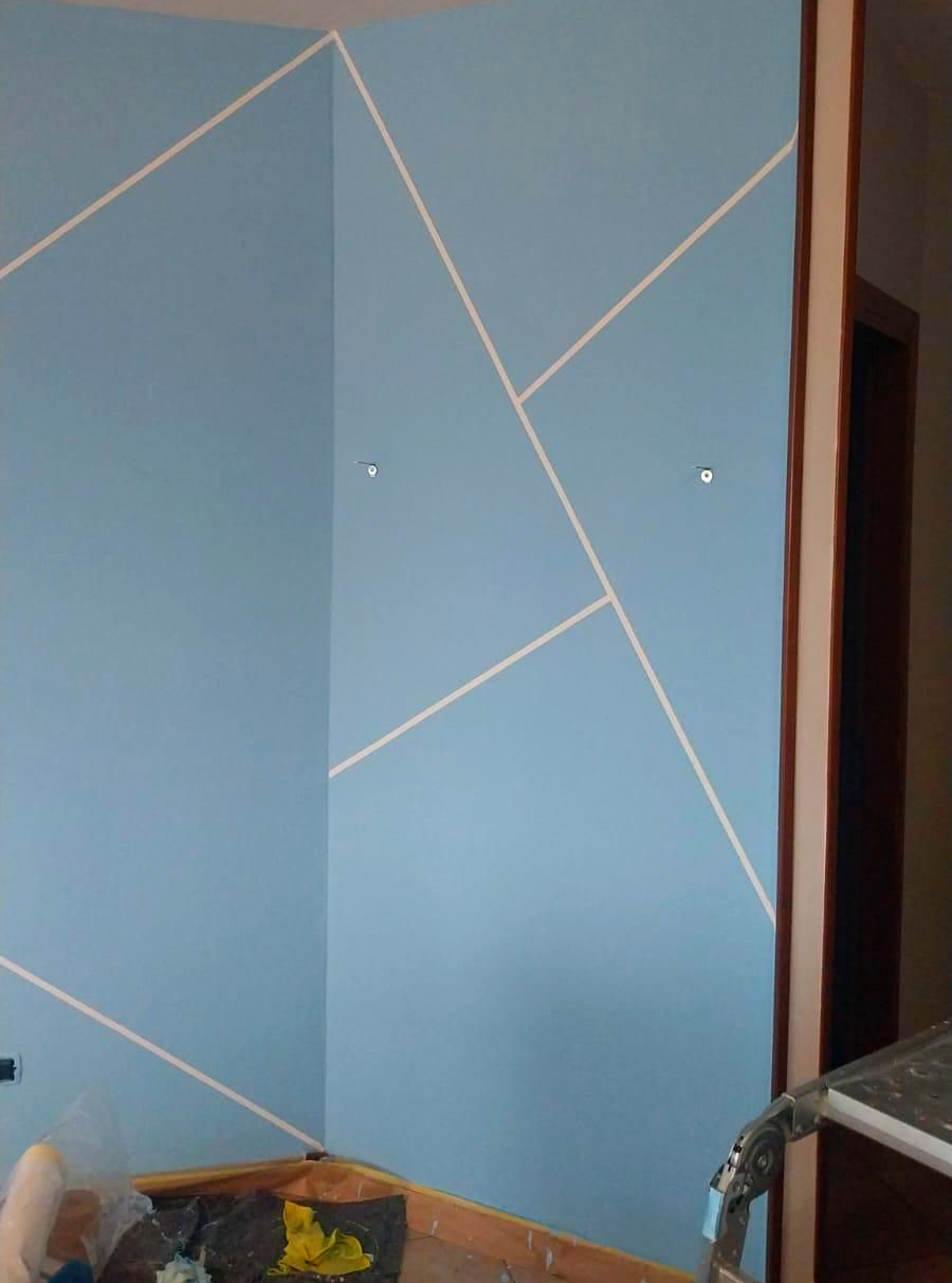 Parete azzurra con linee geometriche bianche.