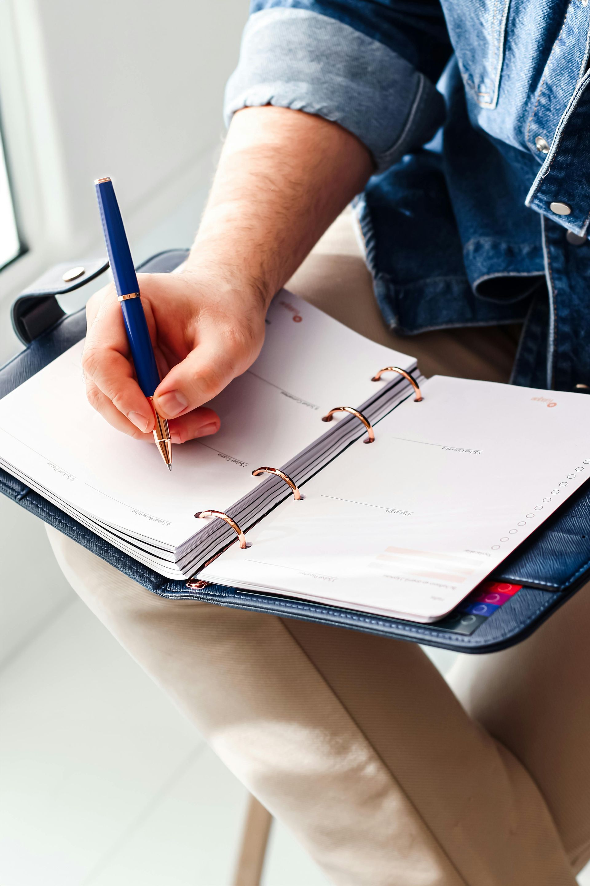 A person is writing in a notebook with a pen.