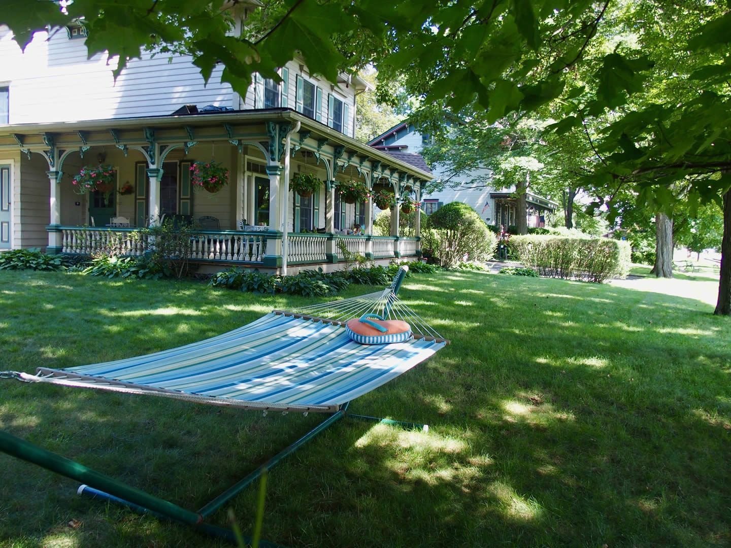 A hammock in front of a house with a porch