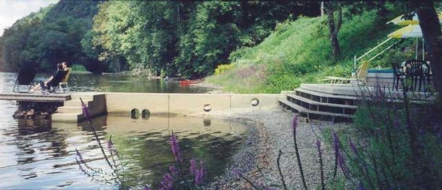 A person is sitting on a dock next to a lake.