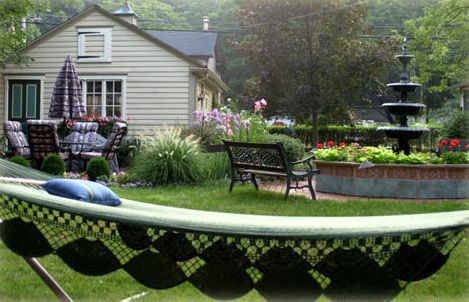A hammock is sitting in the grass in front of a house