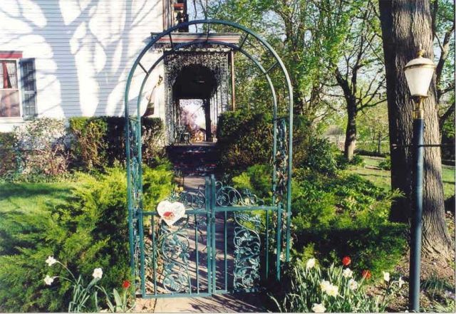 A green gate with a heart on it leads to a house