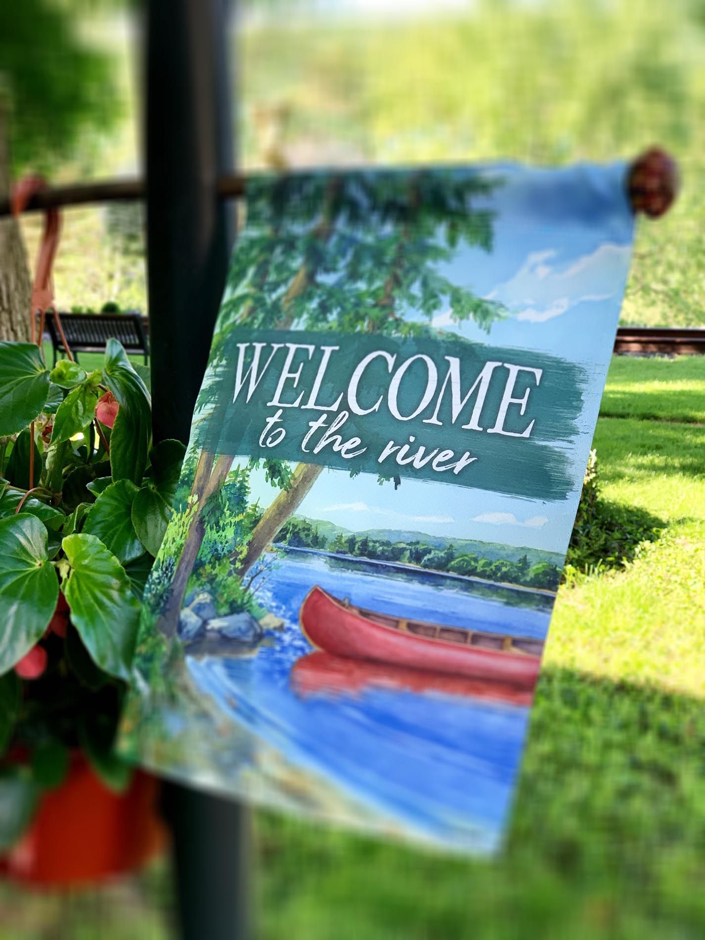 A welcome to the river garden flag is hanging on a pole.
