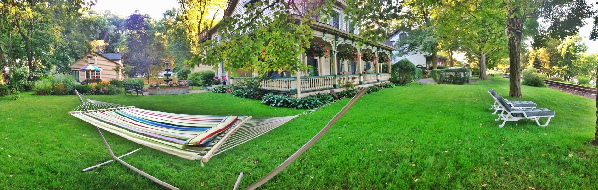 A hammock is sitting in the grass in front of a house.