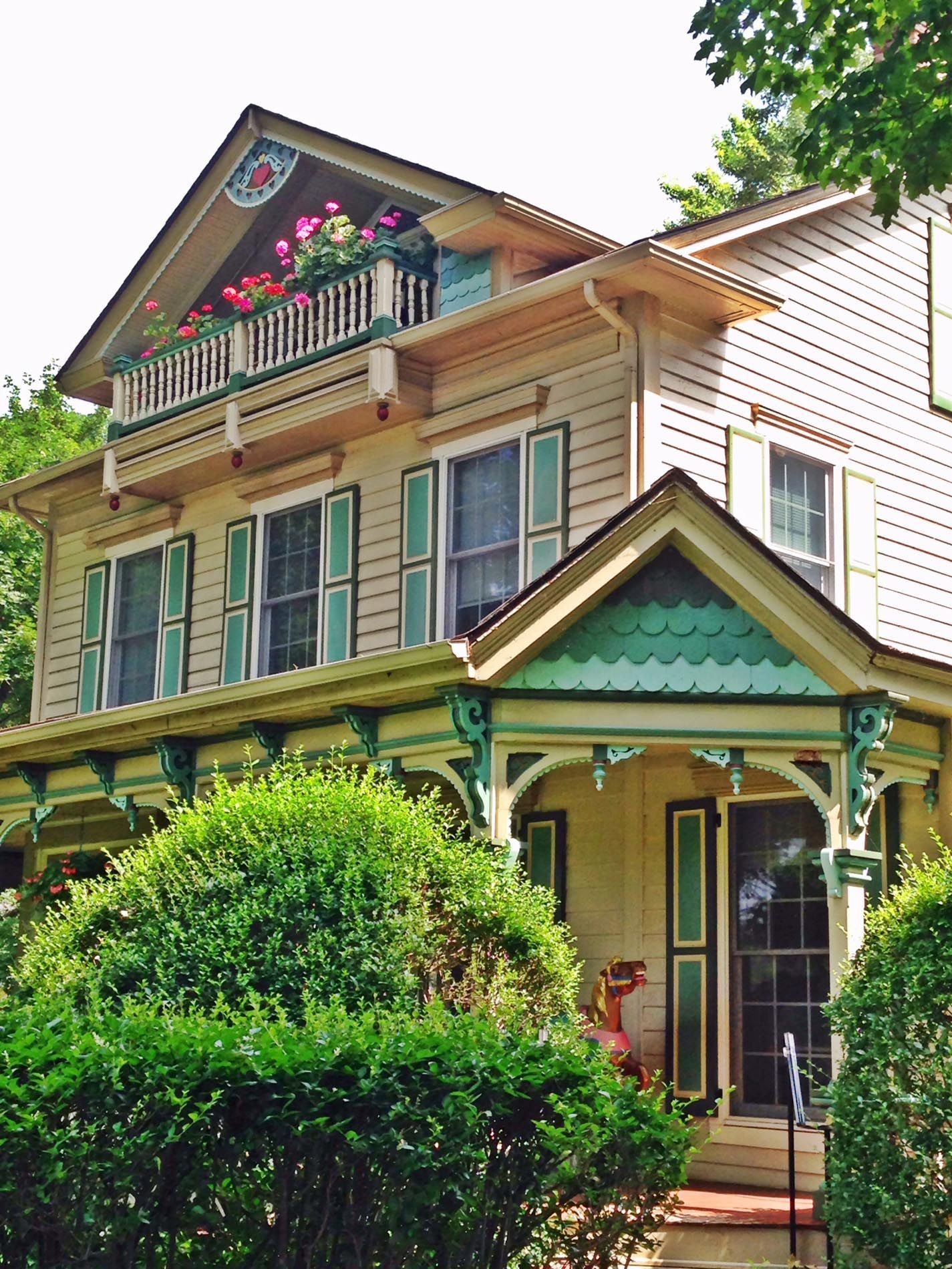 A white house with green shutters and a balcony